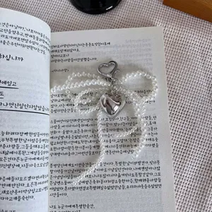 Ασημένιο μπρελόκ με φιόγκο από πέρλες και καρδιά, κομψό και μοντέρνο αξεσουάρ τσάντας.