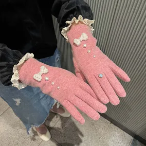 Dettaglio in primo piano di guanti invernali da donna in maglia con fiocchi di perle.