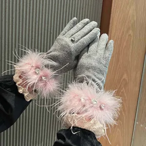 Détail en gros plan de gants en cachemire gris avec plumes d'autruche roses et strass.
