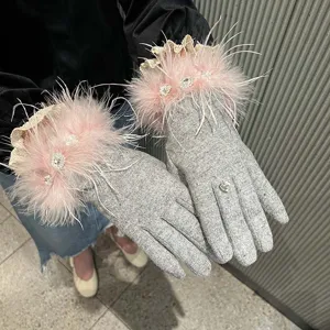 Gros plan détail de gants pour femmes vintage en tricot gris avec des plumes roses.