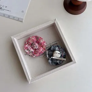 Detail view of handmade tweed camellia flower brooch and hair clip in dual color tones.