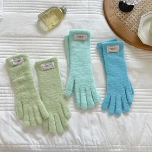 Close-up detail of soft fuzzy knit touchscreen gloves in pastel colors with cute label patch.