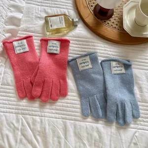 Primer plano de guantes de invierno de punto cálido en rosa y azul con etiquetas en el puño.