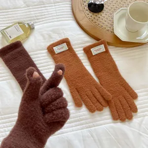 Detail shot of cozy winter knit touch screen gloves in soft warm colors on cozy bed background.