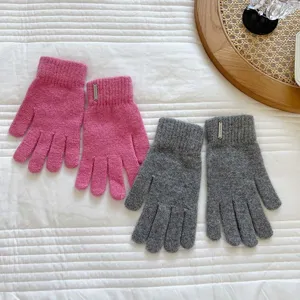 Close-up detail of warm winter knit gloves in pink and grey colors featuring chic metal tags.