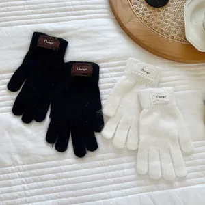 Detailed view of cozy knitted full-finger gloves in black and white with chic woven patch accents.
