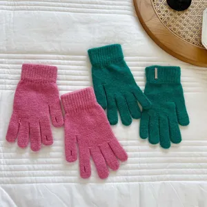 Detailed view of autumn and winter knitted finger gloves in pink and green with metal charm.