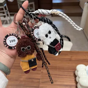 Close-up of cute plush teddy bear and puppy bag keychain charm with leather outfit.