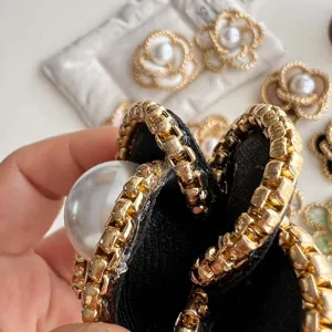 Detail view of luxury camellia brooch featuring chunky gold chain and pearl embellishment.