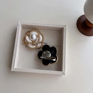 Close-up of elegant Chanel-style camellia brooch and hair clip set in white tray.