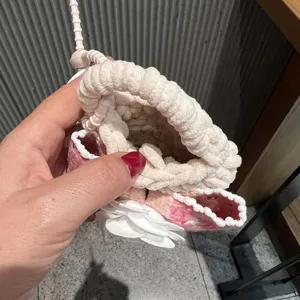 Handmade knitted mini pouch earphone case with white flower pendant and strap detail.