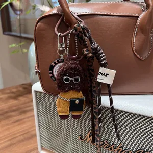 Cute curly puppy plush bag charm detail shot, premium leather teddy bear keychain pendant for handbags.