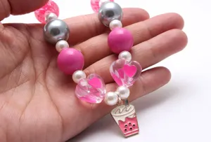 Nahaufnahme der detailreichen Kinder Perlenkette mit rosa Kugeln und süßem Milchtee Anhänger.
