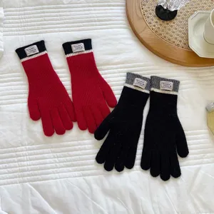 Detailed shot of cozy color-blocked knitted gloves in red and black for winter warmth.