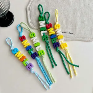 Colorful beaded weave bag charm detail shot featuring cheerful smile letter charms and cord.