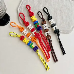 Detailed view of colorful braided rope bag charms with smile letter beads, vibrant accessory.