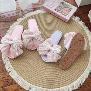 Nahaufnahme von süßen rosa und lila Rüschen Schleife Stoff Hausschuhen auf Matte.