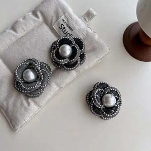 Elegant black fabric camellia flower brooch with central pearl accent for women's stylish outfits.