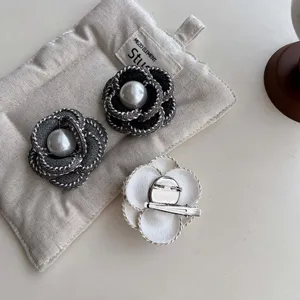 Detail view of pearl fabric camellia brooch, textured weaving edge and secure clasp.