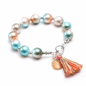 Vue detaillee du bracelet de perles colorees pour enfants avec coquillage et pompons.