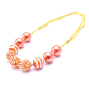 Close-up of children chunky beaded necklace with resin rhinestone balls and adjustable yellow cord.