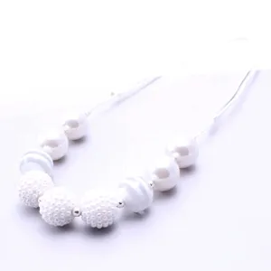 Close up detail of white resin beaded necklace with textured spheres and adjustable cord.