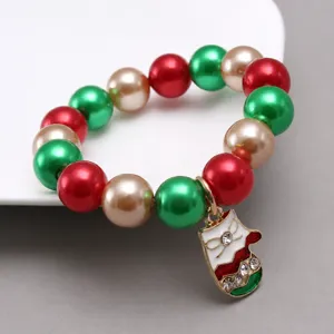 Detailed close-up of kids Christmas beaded bracelet with red green pearls and rhinestone pendant.