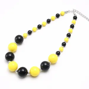 Close-up detail of black and yellow chunky acrylic bead necklace with silver chain.