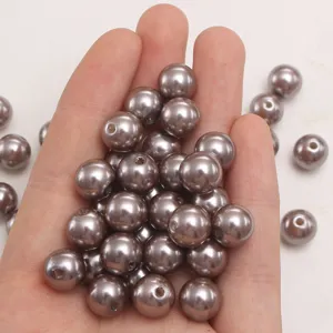 Primo piano di perle in ABS color caffè fumé sfuse, perfette per creazioni fai da te.