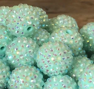 Primo piano di perline in resina strass verde menta, sfere artigianali fai-da-te scintillanti.