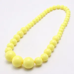 Close-up detail of the yellow acrylic bead children necklace, showing smooth glossy bead surface.