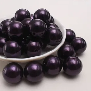 Gros plan de perles d'imitation en plastique ABS violet foncé avec un design rond lisse.