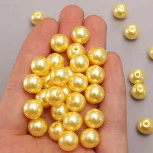 Primer plano de perlas de imitación de plástico ABS amarillo oscuro, superficie lisa, DIY.