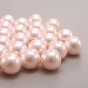 Gros plan de perles d'imitation en plastique ABS rose clair avec surface lisse et trou.