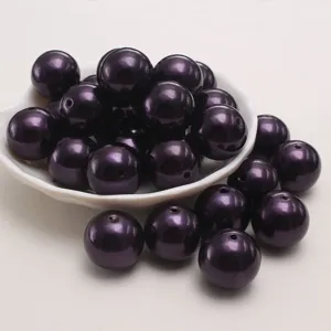 Gros plan détaillé de perles d'imitation ABS bordeaux foncé présentées dans un plat.