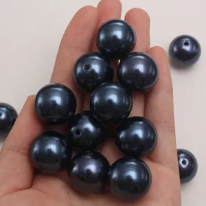 Close-up view of dark blue ABS plastic imitation pearl loose beads held in hand for DIY.