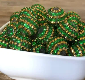 Close-up detail of dark green and gold rhinestone chunky resin ball beads for jewelry crafts.