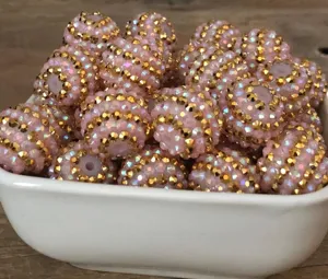 Detailaufnahme schimmernder rosa Strassperlen mit goldenen Streifen für DIY-Handarbeit.