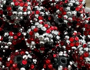 Primer plano detallado de cuentas de resina con pedreria roja, plateada y negra para DIY.