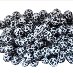 Close-up detail of black and white resin rhinestone beads with cow print pattern.