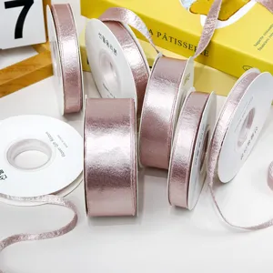 Pink glossy satin ribbon rolls, shimmering fabric for DIY bows, hair accessories and crafts.