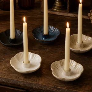 Detail du bougeoir en ceramique avec base en forme de petale et bougie allumee pour la decoration.