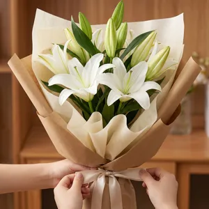 Bouquet de lys blancs emballé dans du papier kraft et du tissu étanche pour cadeaux.
