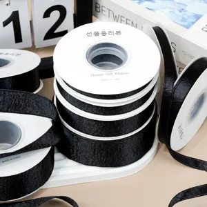 Black shiny ribbon spool detail, smooth satin texture for DIY crafts and gift wrapping.
