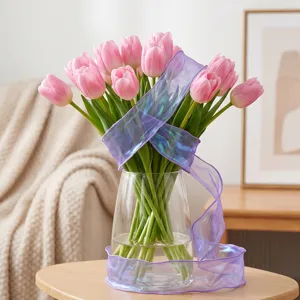 Mazzo di tulipani rosa in vaso di vetro con nastro viola iridescente per decorazione.