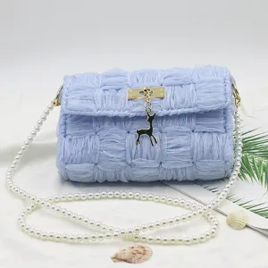 Borsa a tracolla intrecciata azzurro chiaro con tracolla di perle e ciondolo cervo.