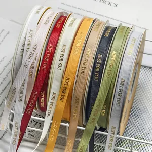 Colorful grosgrain ribbon rolls with gold printed text for gift box packaging and flower bouquets.