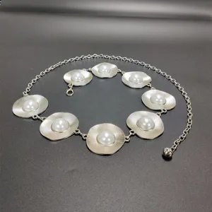 Silver metal waist chain with circular textured discs and faux pearls for women. Detail shot.