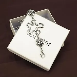 Détail de chaîne de taille en métal argenté avec des charms roses sur boîte cadeau blanche.