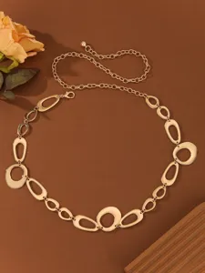 Closeup of gold metal chain belt, geometric rings and fine links detail for stylish dress decor.